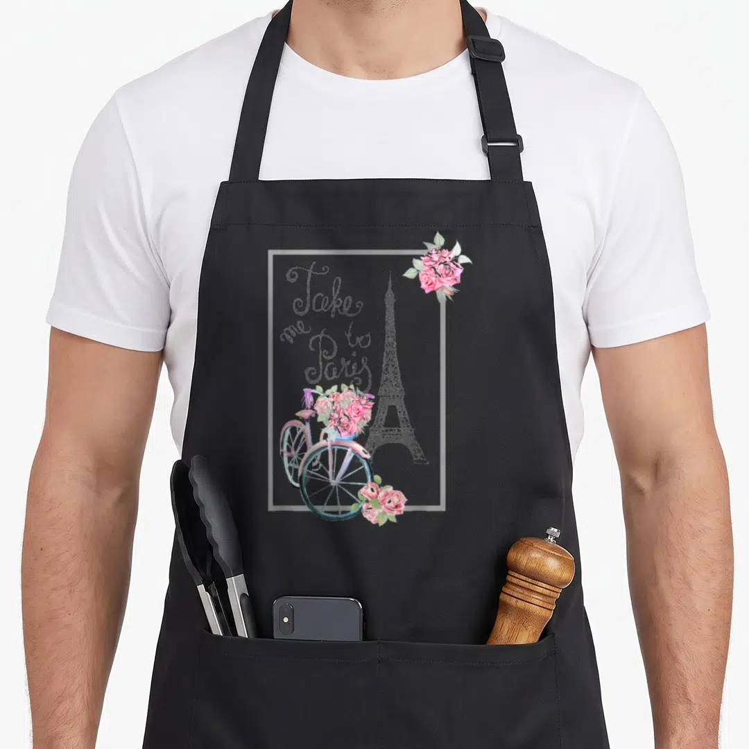 Paris french apron - Watercolor Eiffel Tower, bicycle with pink roses, and script text Take me to Paris inside a white — shown on a black cotton canvas apron against a white background