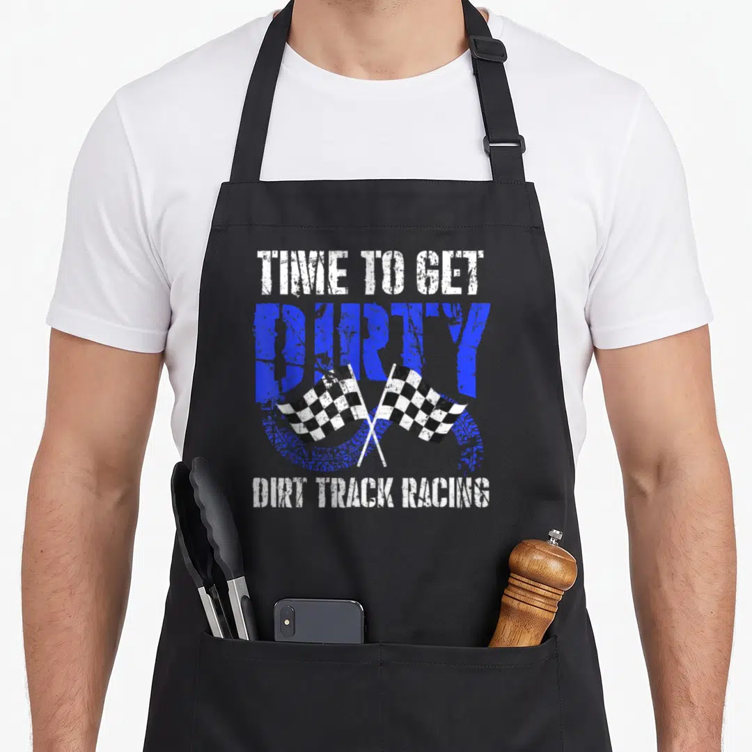 Dirty track apron - Stacked distressed text with two crossed checkered flags over a blue tire track circle — shown on a black cotton canvas apron against a white background