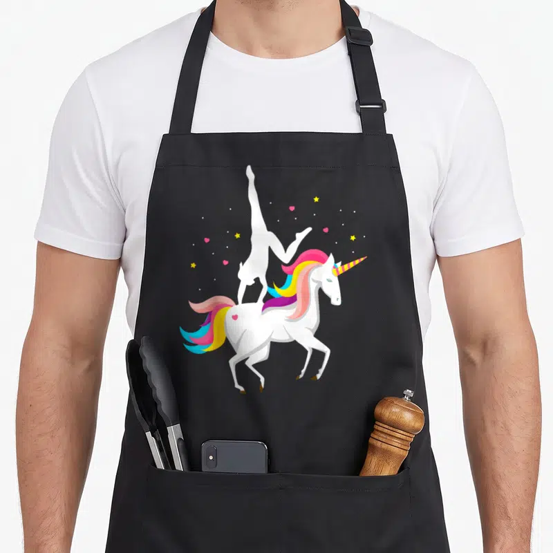 Acrobatic horse apron - White unicorn with rainbow mane and vaulting silhouette surrounded by stars and hearts — shown on a black cotton canvas apron against a white background