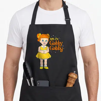 Hello camping apron - Cartoon girl with orange hair and yellow dress next to Hello I'm Gabby Gabby text — shown on a black cotton canvas apron against a white background