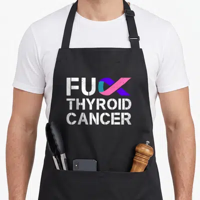 Cancer thyroid apron - White stacked text with purple pink teal ribbon replacing K in first word — shown on a black cotton canvas apron against a white background