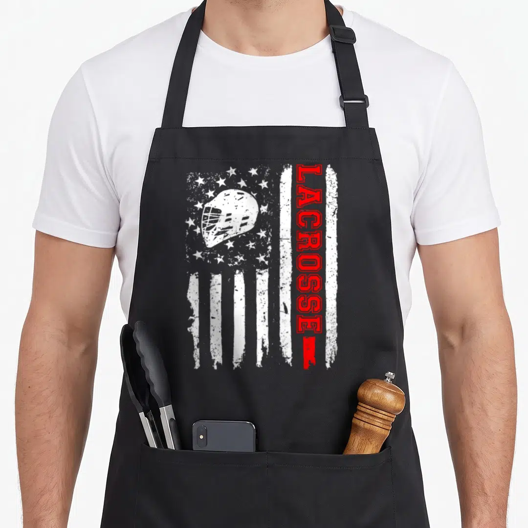 Lacrosse american flag apron - Distressed white and red flag with white helmet and vertical red LACROSSE text — shown on a black cotton canvas apron against a white background