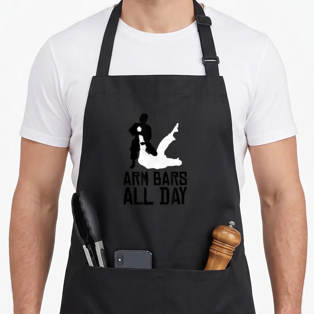 Bar arm day apron - Black and white grappling silhouette above stacked text ARM BARS ALL DAY — shown on a black cotton canvas apron against a white background