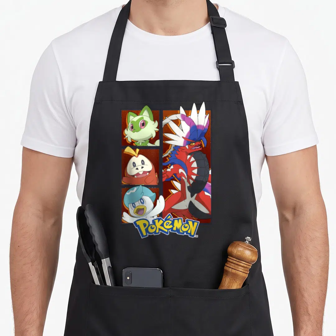 Pok boxed apron - Koraidon and Paldea starters Sprigatito Fuecoco Quaxly four-panel cartoon design — shown on a black cotton canvas apron against a white background