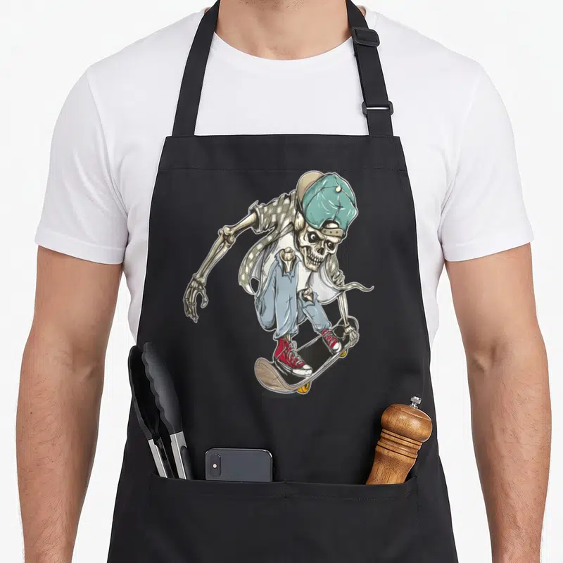 Extreme skeleton apron - Cartoon skeleton in streetwear riding skateboard with teal hat and red shoes — shown on a black cotton canvas apron against a white background