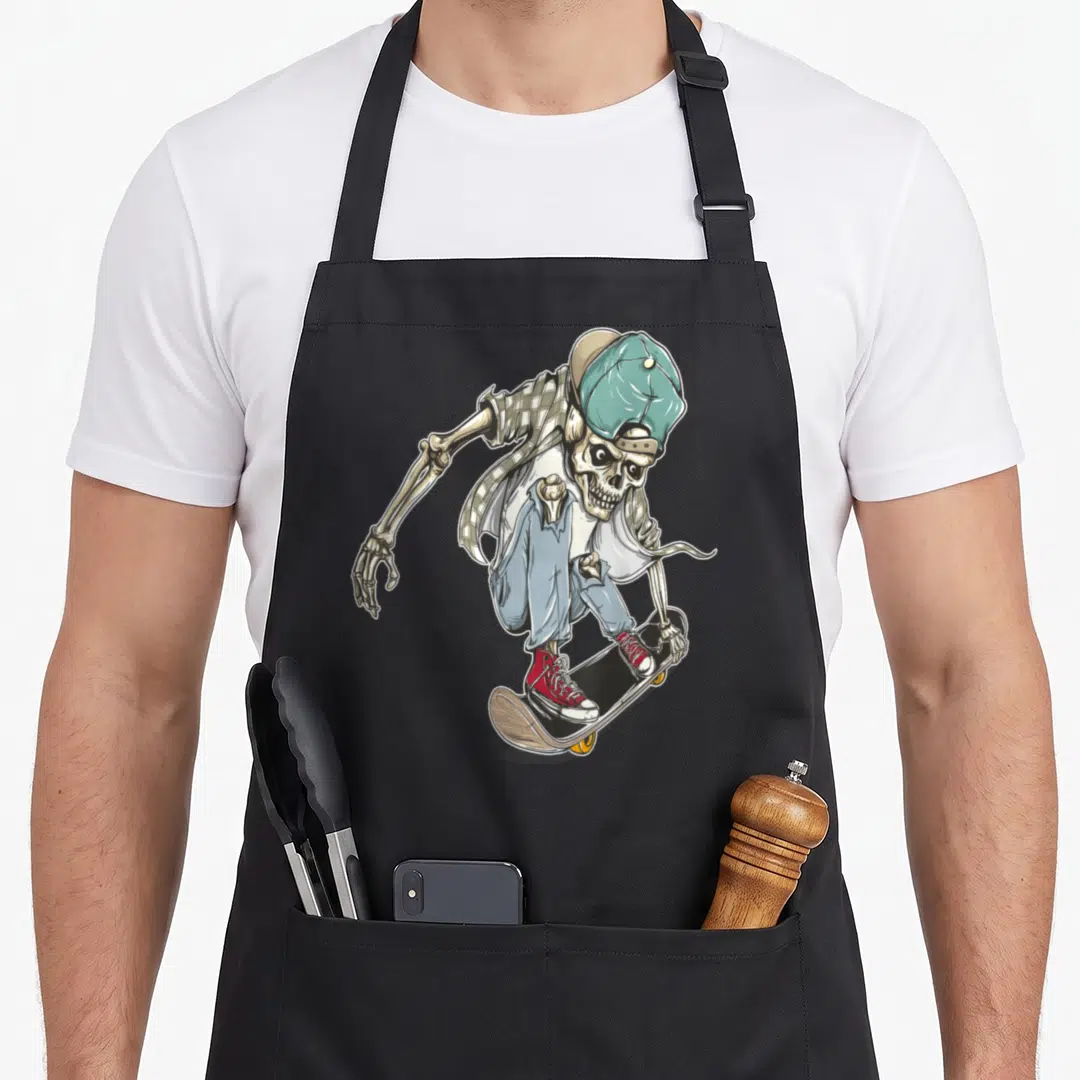 Extreme skeleton apron - Cartoon skeleton in streetwear riding skateboard with teal hat and red shoes — shown on a black cotton canvas apron against a white background
