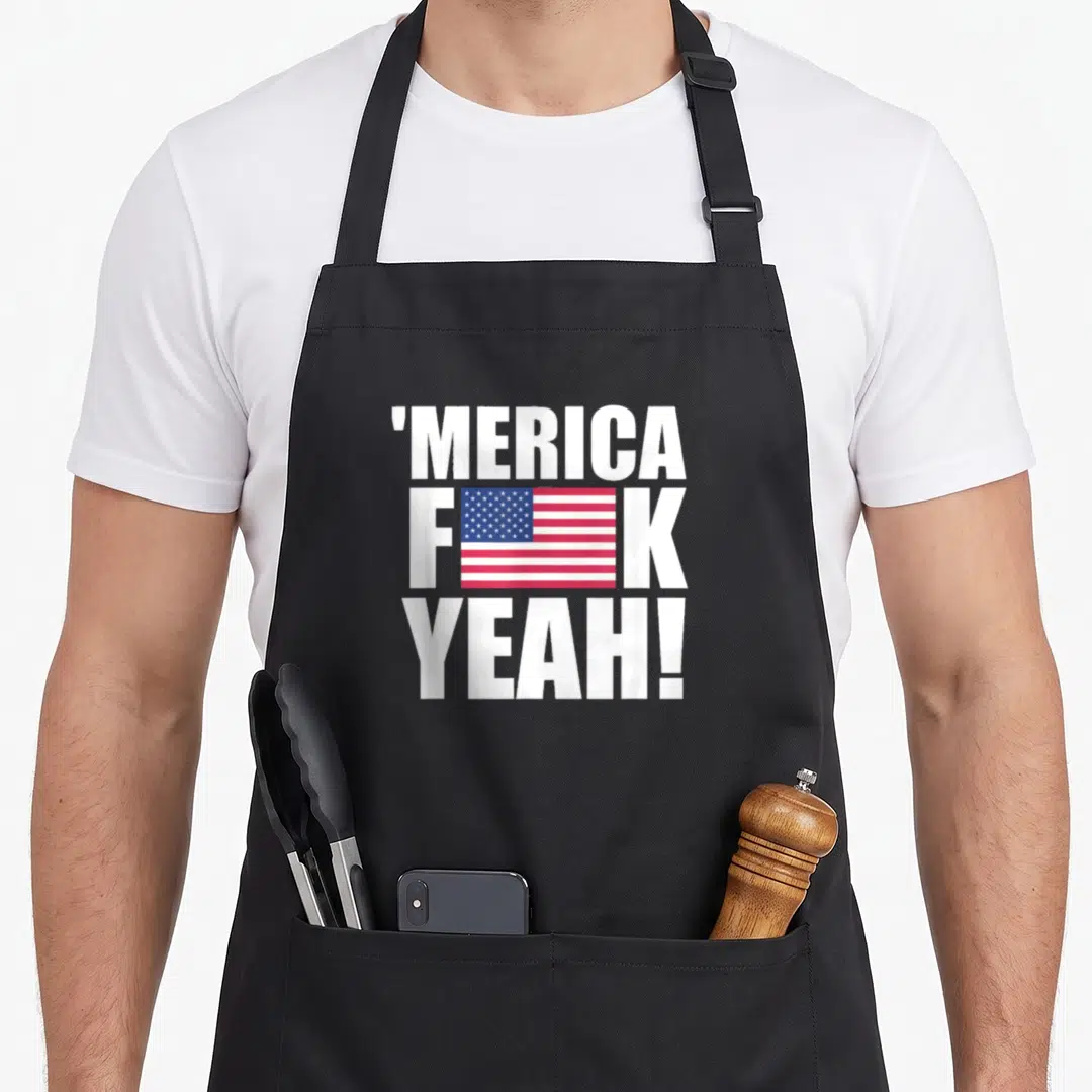 Yeah fourth of july aprons - Stacked white 'MERICA F K YEAH text with USA flag graphic replacing letter U — shown on a black cotton canvas apron against a white background