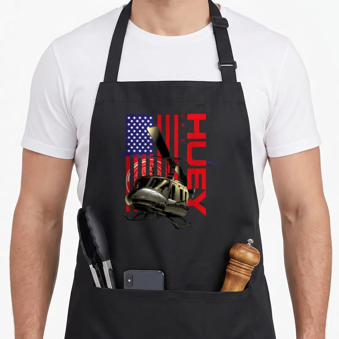 Warbird military apron - Realistic helicopter graphic over USA flag with vertical HUEY and U H - 1 text in red and gold — shown on a black cotton canvas apron against a white background