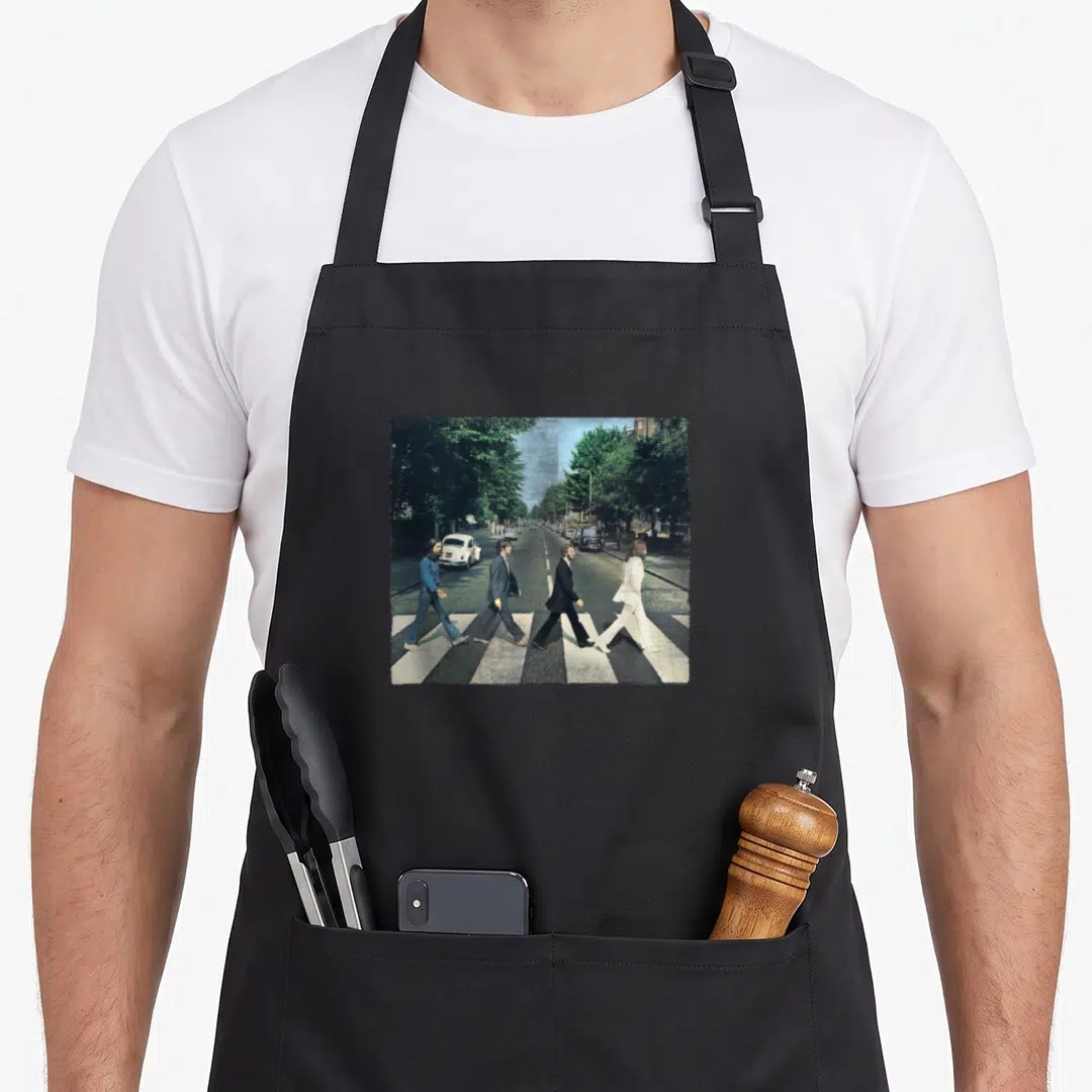 Crossing road apron - Four people walking across a zebra crosswalk in a city street photo — shown on a black cotton canvas apron against a white background