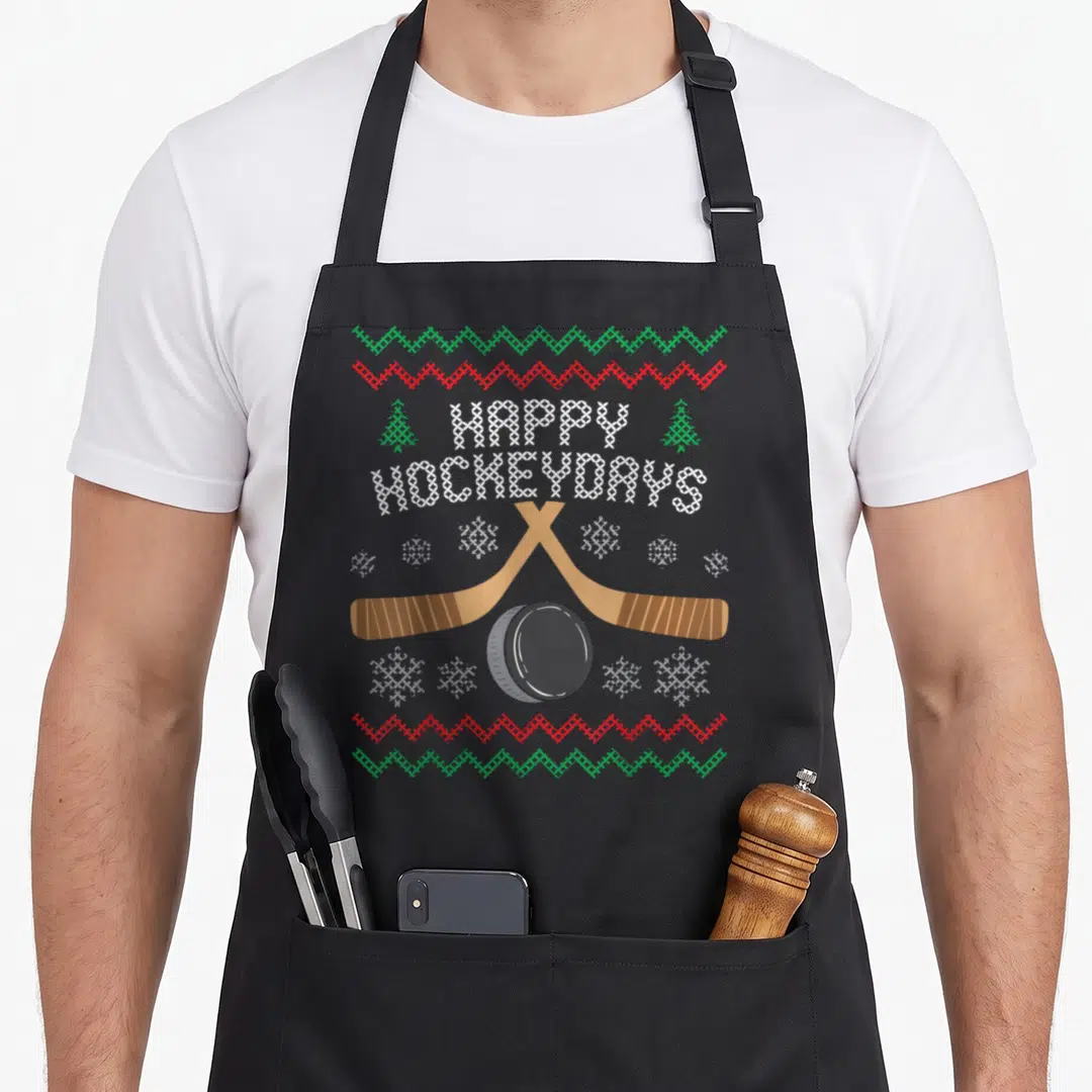 Hockeyday ugly christmas sweater apron - Retro knit style graphic with crossed brown sticks, black puck, and white — shown on a black cotton canvas apron against a white background