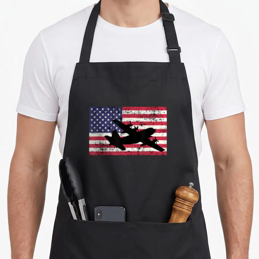 Patriotic airplane apron - Black C-130 Hercules silhouette over distressed red white blue USA flag — shown on a black cotton canvas apron against a white background