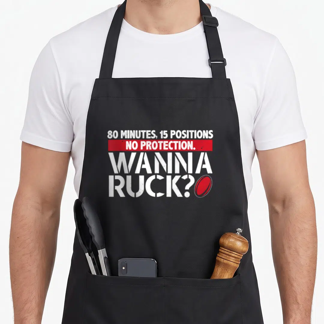 Ruck rugby player apron - White and red text reading 80 minutes 15 positions no protection wanna ruck next to a rugby — shown on a black cotton canvas apron against a white background