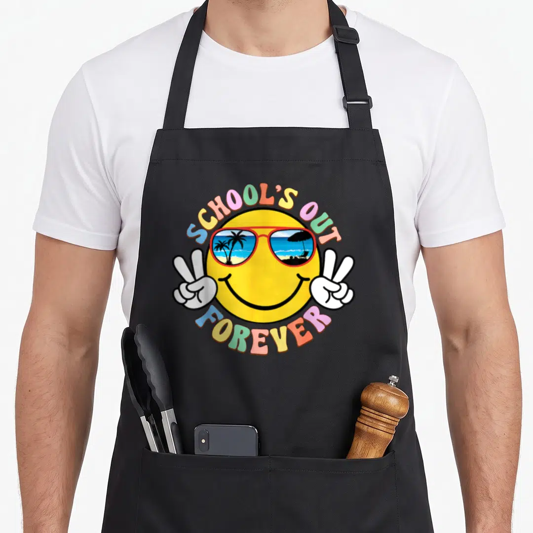 Groovy teachers apron - Yellow smiley face with beach reflection sunglasses and two white peace sign hands surrounded — shown on a black cotton canvas apron against a white background
