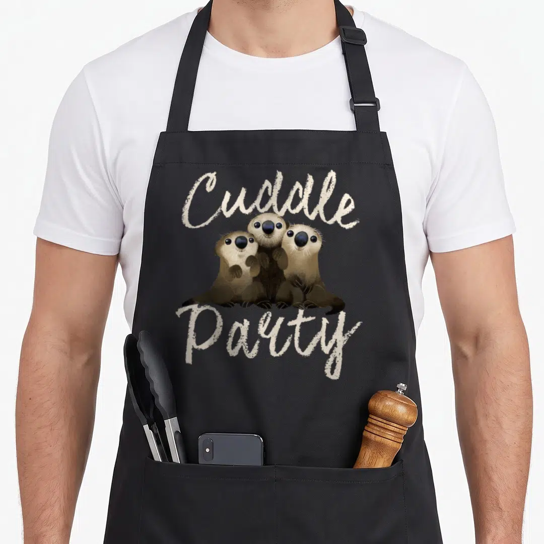 Finding sea otter apron - Three brown cartoon otters huddled under beige Cuddle Party script text — shown on a black cotton canvas apron against a white background