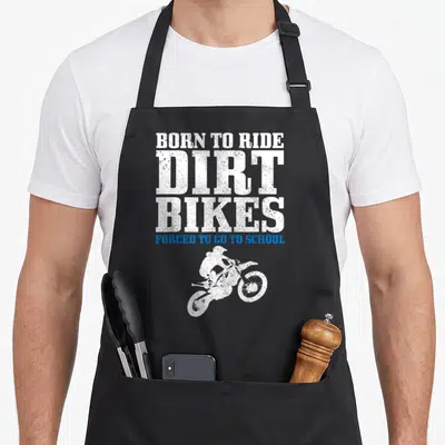 Motocross forced bike apron - Distressed white and blue text reading Born to Ride Dirt Bikes with rider silhouette — shown on a black cotton canvas apron against a white background