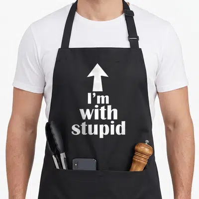 Arrow stupid aprons - White up arrow above I'm with stupid stacked text — shown on a black cotton canvas apron against a white background