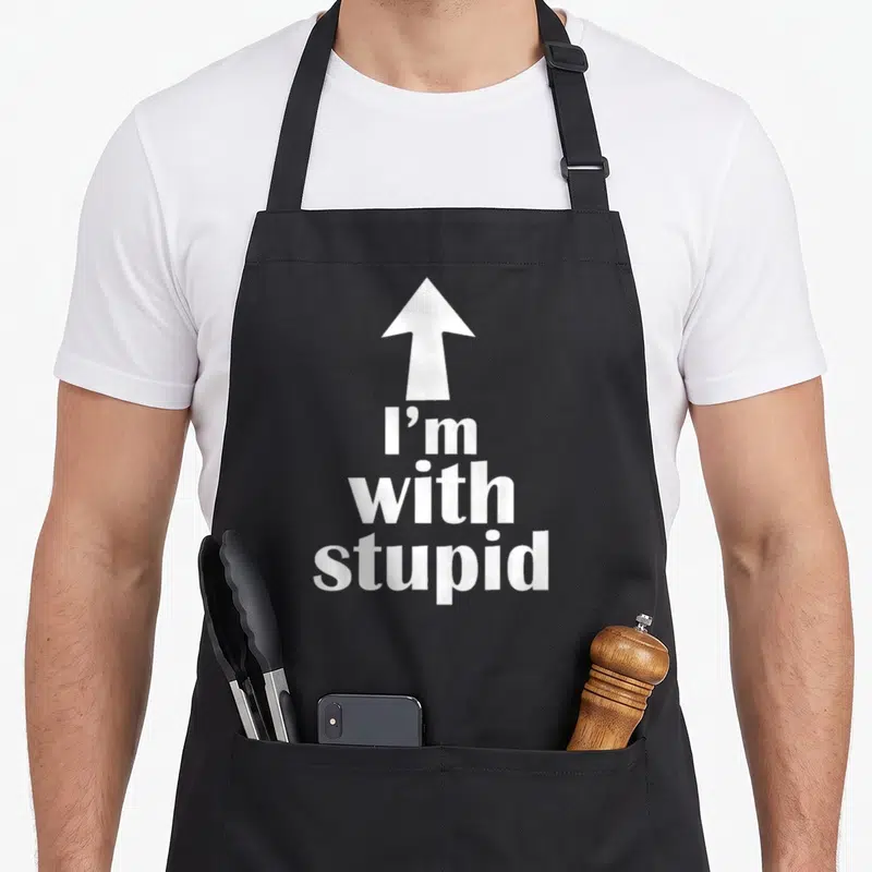 Arrow stupid aprons - White up arrow above I'm with stupid stacked text — shown on a black cotton canvas apron against a white background