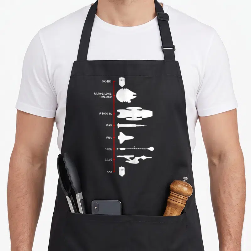 Spaceship science apron - Red vertical line with white spaceship silhouettes and dates like 1967 and 2001 — shown on a black cotton canvas apron against a white background