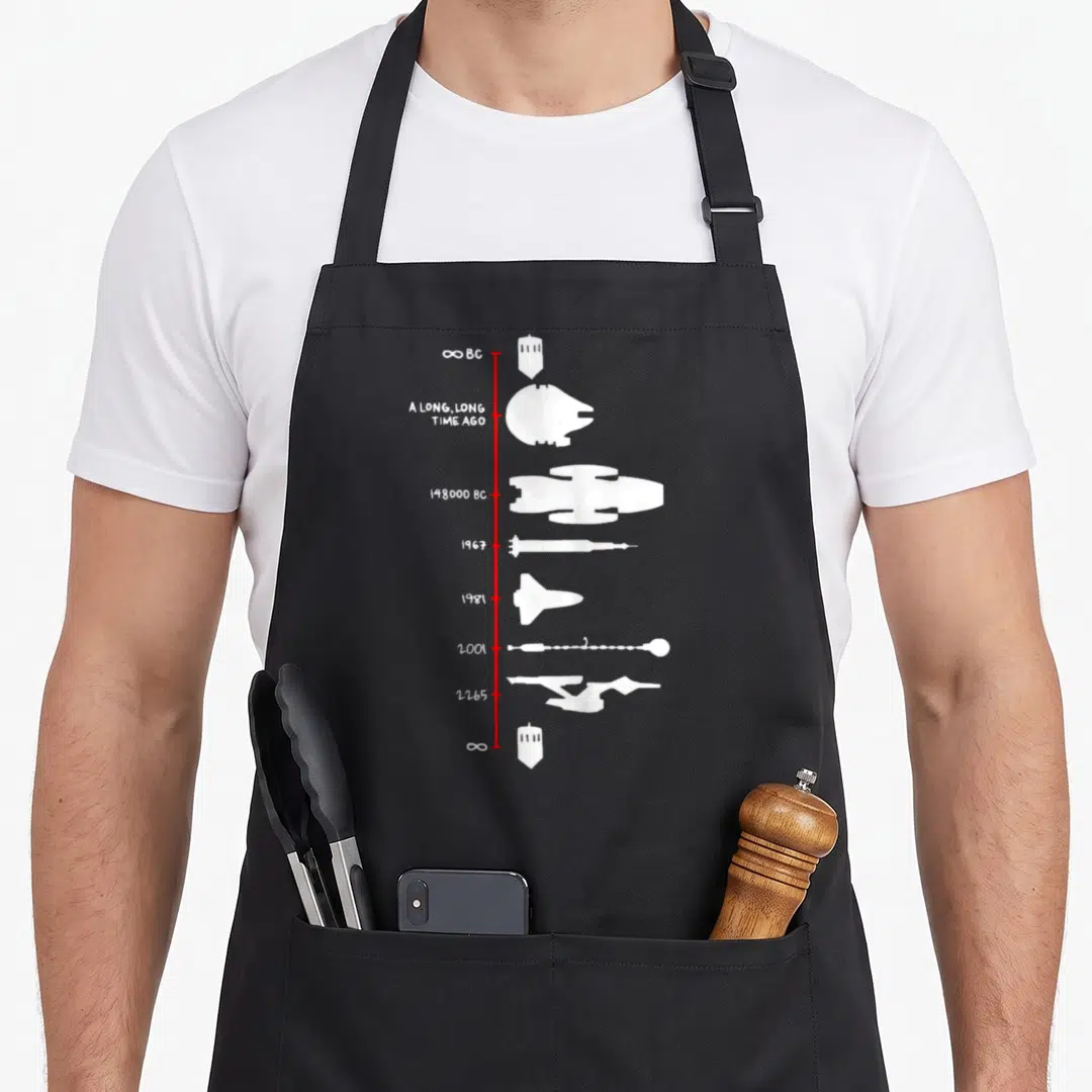 Spaceship science apron - Red vertical line with white spaceship silhouettes and dates like 1967 and 2001 — shown on a black cotton canvas apron against a white background