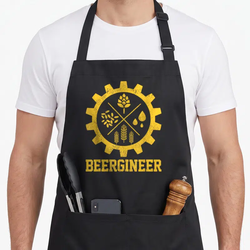 Beergineer beer brewing apron - Yellow gear with four ingredients and distressed BEERGINEER text — shown on a black cotton canvas apron against a white background