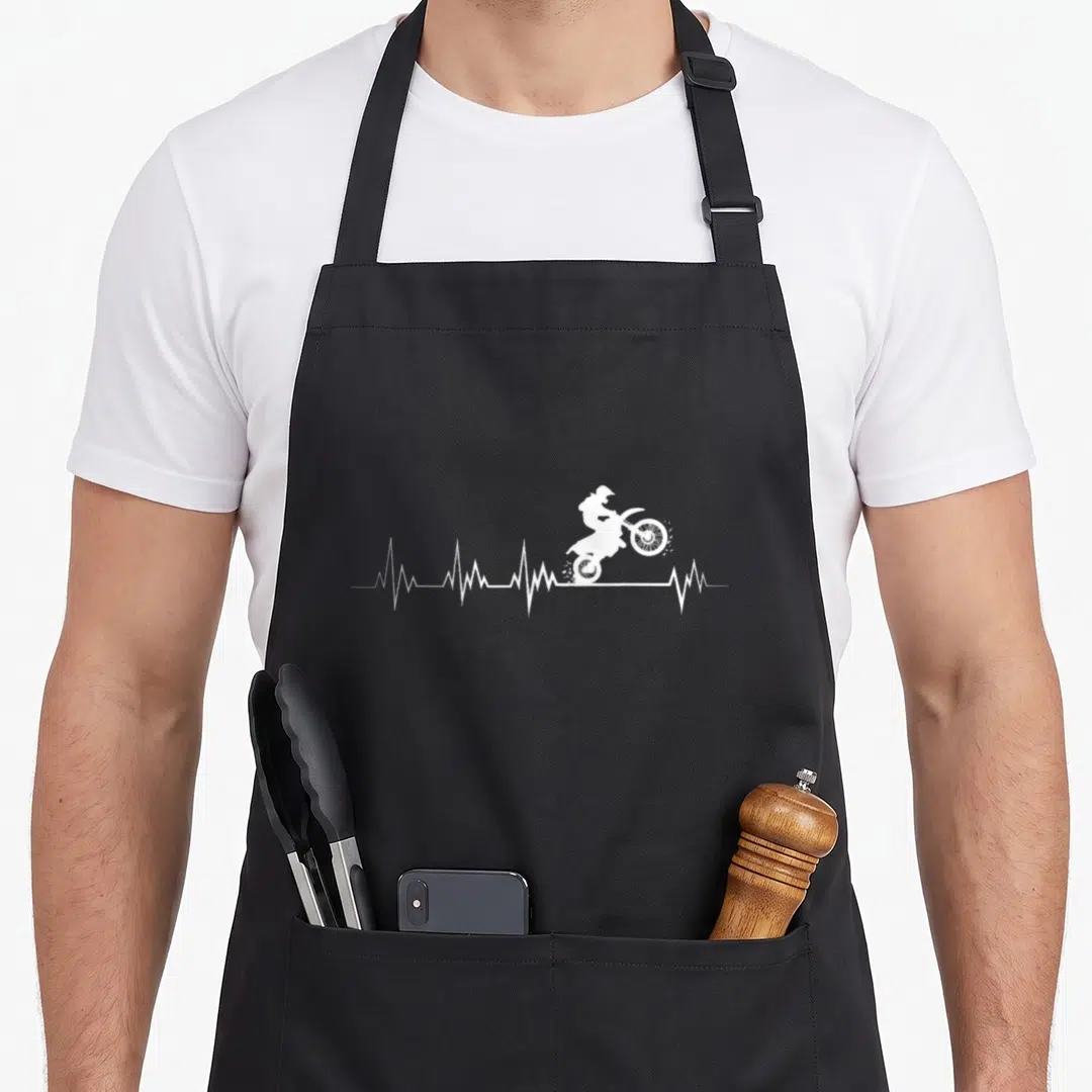 Motorcross bike apron - White silhouette of motocross rider on bike inside a horizontal heartbeat line — shown on a black cotton canvas apron against a white background