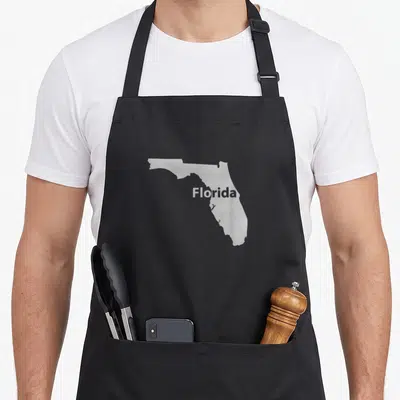 Florida outline of an apron - Light grey map of Florida with white text centered on front panel — shown on a black cotton canvas apron against a white background