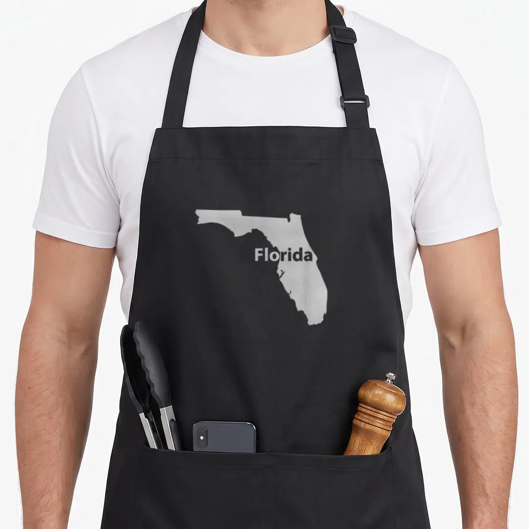 Florida outline of an apron - Light grey map of Florida with white text centered on front panel — shown on a black cotton canvas apron against a white background