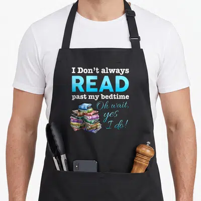 Alway i love reading apron - Stacked colorful books with typography reading I Don't always READ past my bedtime — shown on a black cotton canvas apron against a white background