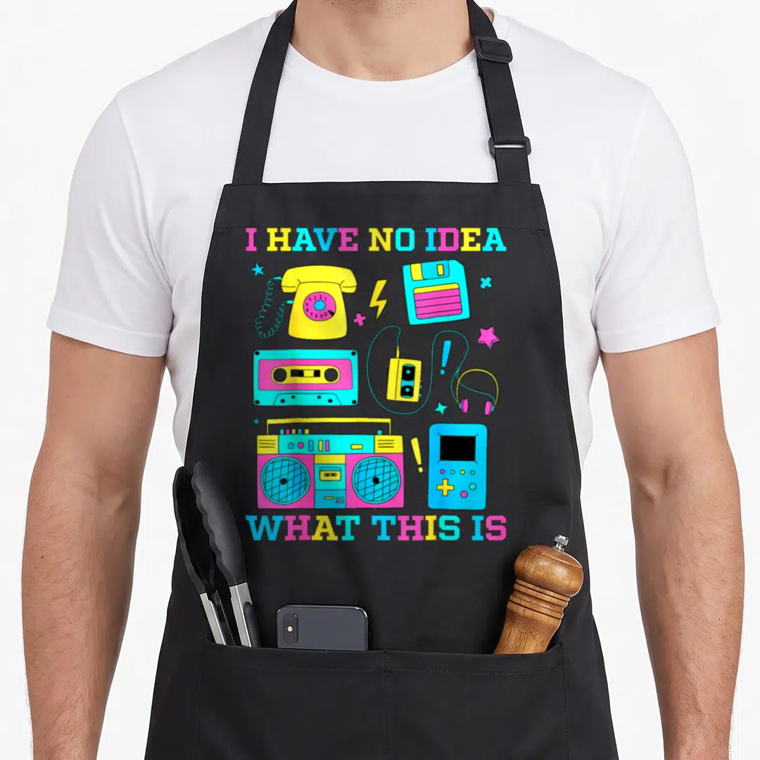Theme chef outfit with apron - I Have No Idea What This Is text above yellow rotary phone, cassette, boombox, and blue — shown on a black cotton canvas apron against a white background