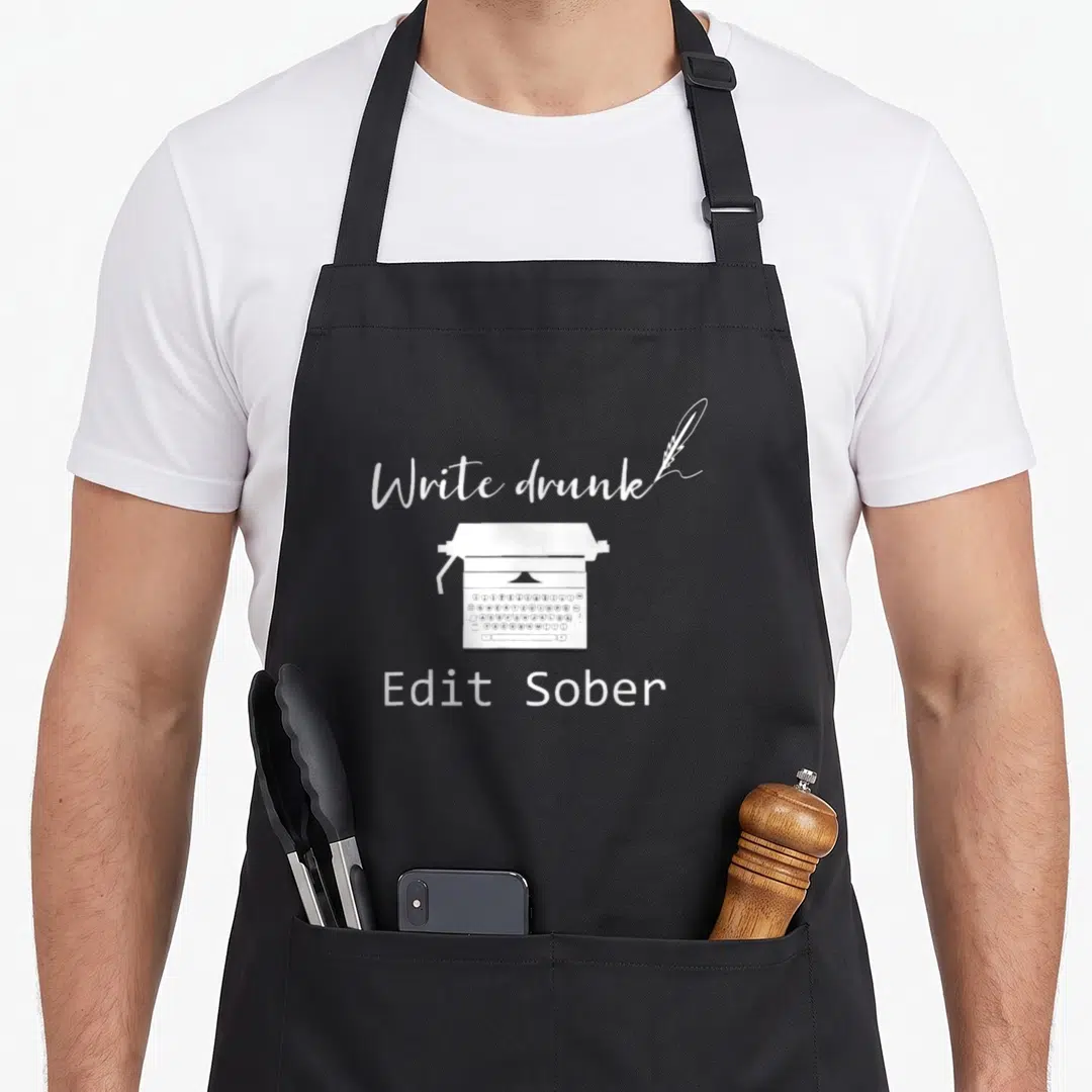 Writer edit apron - White typewriter and quill with Write Drunk Edit Sober text on black fabric — shown on a black cotton canvas apron against a white background