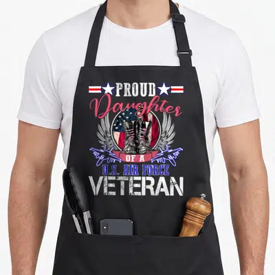 Daughter air force veteran apron - PROUD Daughter OF A U.S. AIR FORCE VETERAN with boots and wings — shown on a black cotton canvas apron against a white background