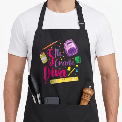 5th school apron - Cartoon 5th Grade Diva text with backpack, glue, ruler, stapler, and stars in pink purple yellow — shown on a black cotton canvas apron against a white background