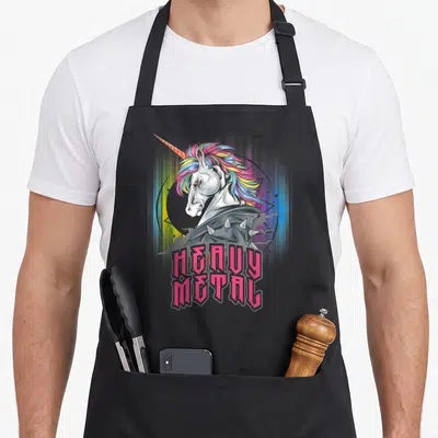 Unicorn heavy apron - Cartoon unicorn with spiked collar and pink heavy metal text — shown on a black cotton canvas apron against a white background