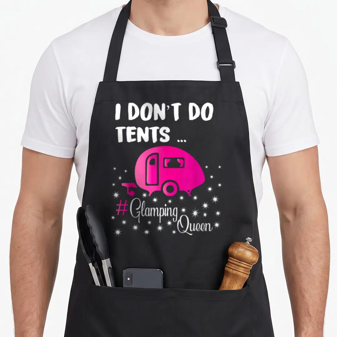 Glamping queen apron - Pink camper trailer with I Don't Do Tents text and scattered stars — shown on a black cotton canvas apron against a white background