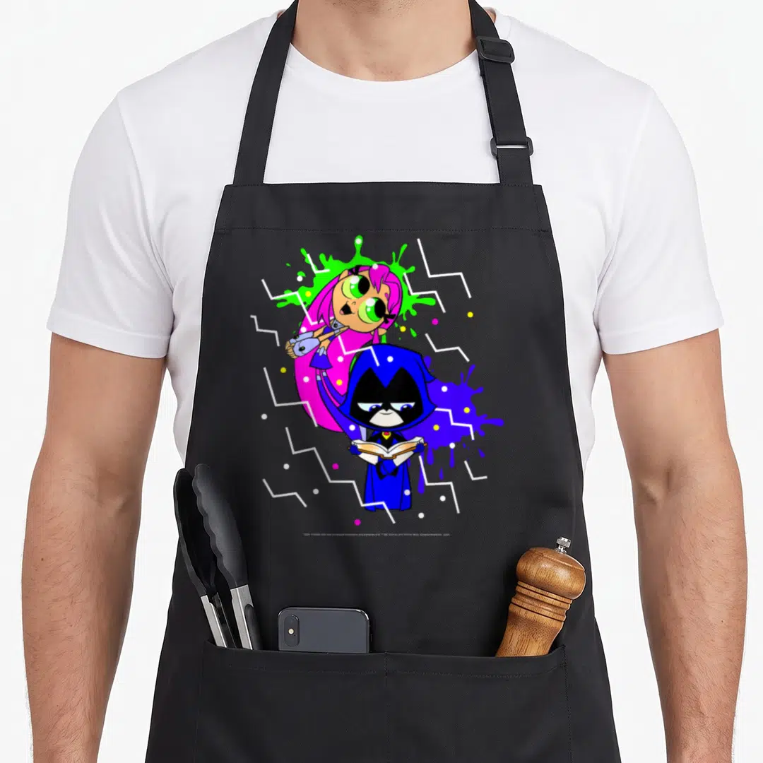 Starfire ravens aprons - Cartoon raven holding book with Starfire behind amidst blue pink green purple splashes — shown on a black cotton canvas apron against a white background