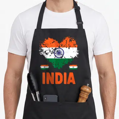 India chef outfit with apron - Distressed heart shaped India flag with two small rectangular flags and orange text below — shown on a black cotton canvas apron against a white background