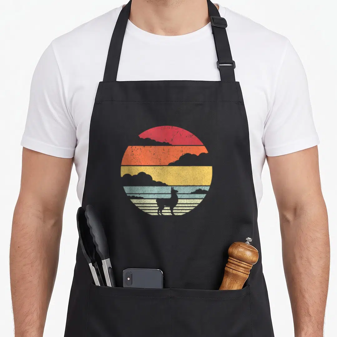 Cute llama alpaca apron - Llama silhouette inside a retro sun with red, orange, yellow, blue, and white horizontal — shown on a black cotton canvas apron against a white background
