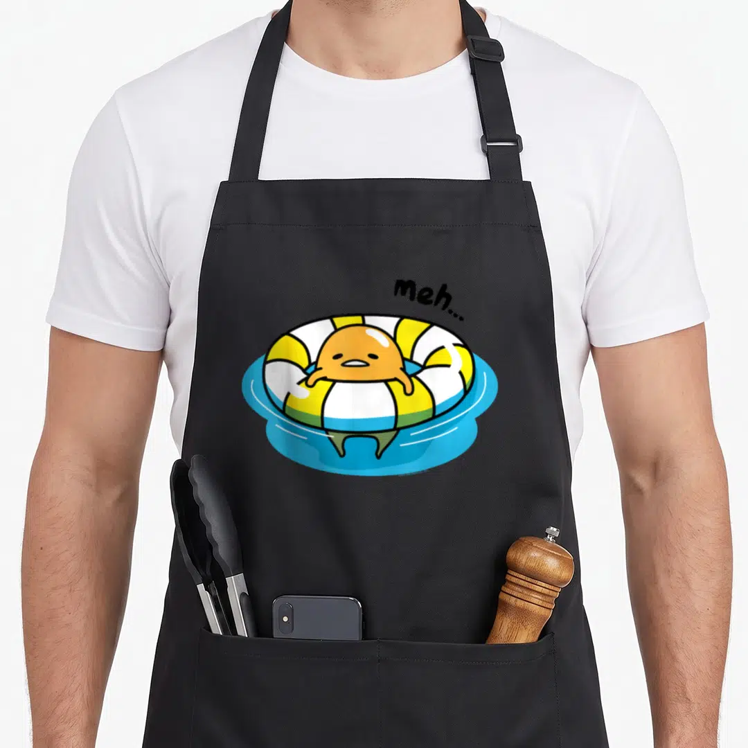Pool gudetama apron - Lazy orange egg in yellow white ring floating on blue water with meh text — shown on a black cotton canvas apron against a white background