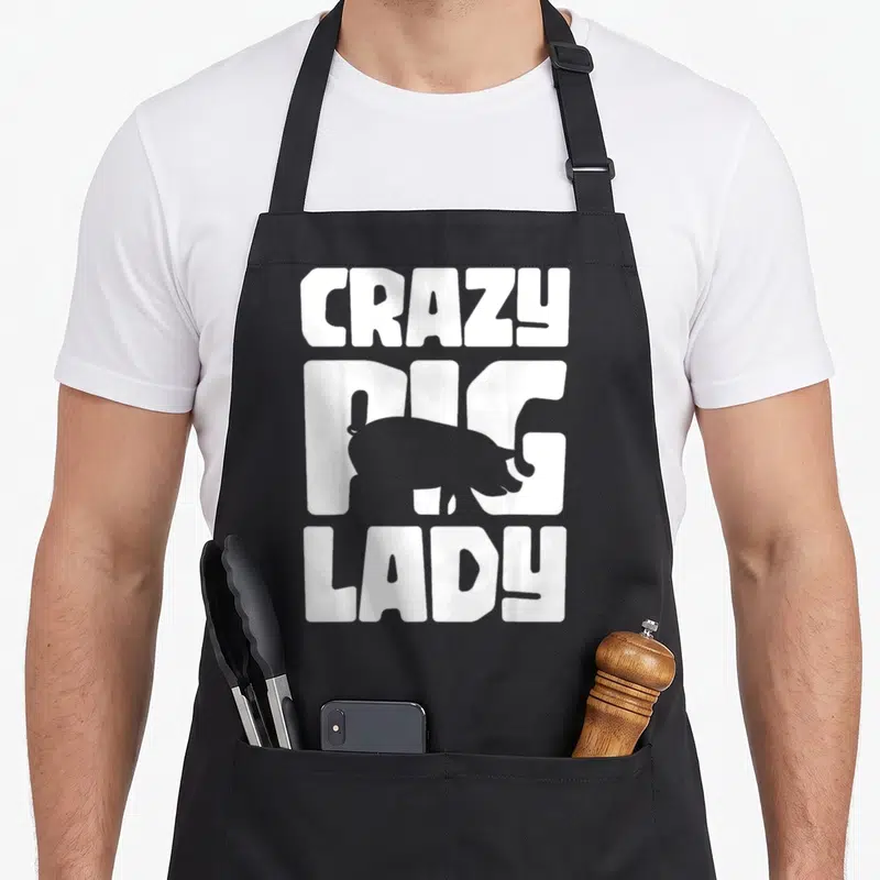 Cute crazy pig man apron - White CRAZY PIG LADY text with grey pig silhouette overlay — shown on a black cotton canvas apron against a white background