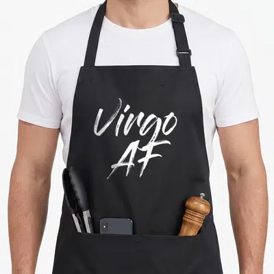 Funny virgo apron - White brush script text Virgo AF stacked on grey background — shown on a black cotton canvas apron against a white background