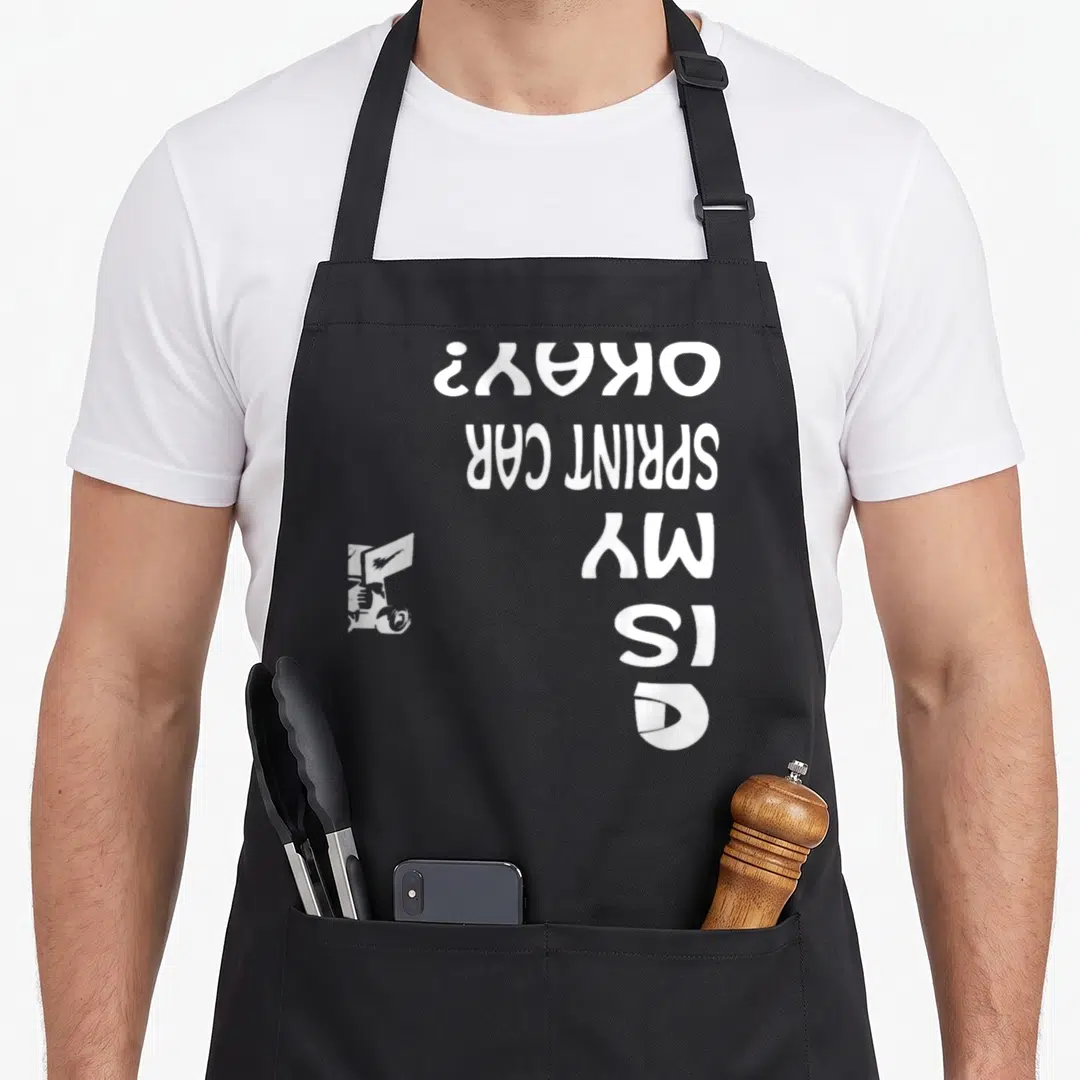 Midget track apron - White sprint car silhouette and stacked text reading IS MY SPRINT CAR OKAY? rotated 90 degrees — shown on a black cotton canvas apron against a white background