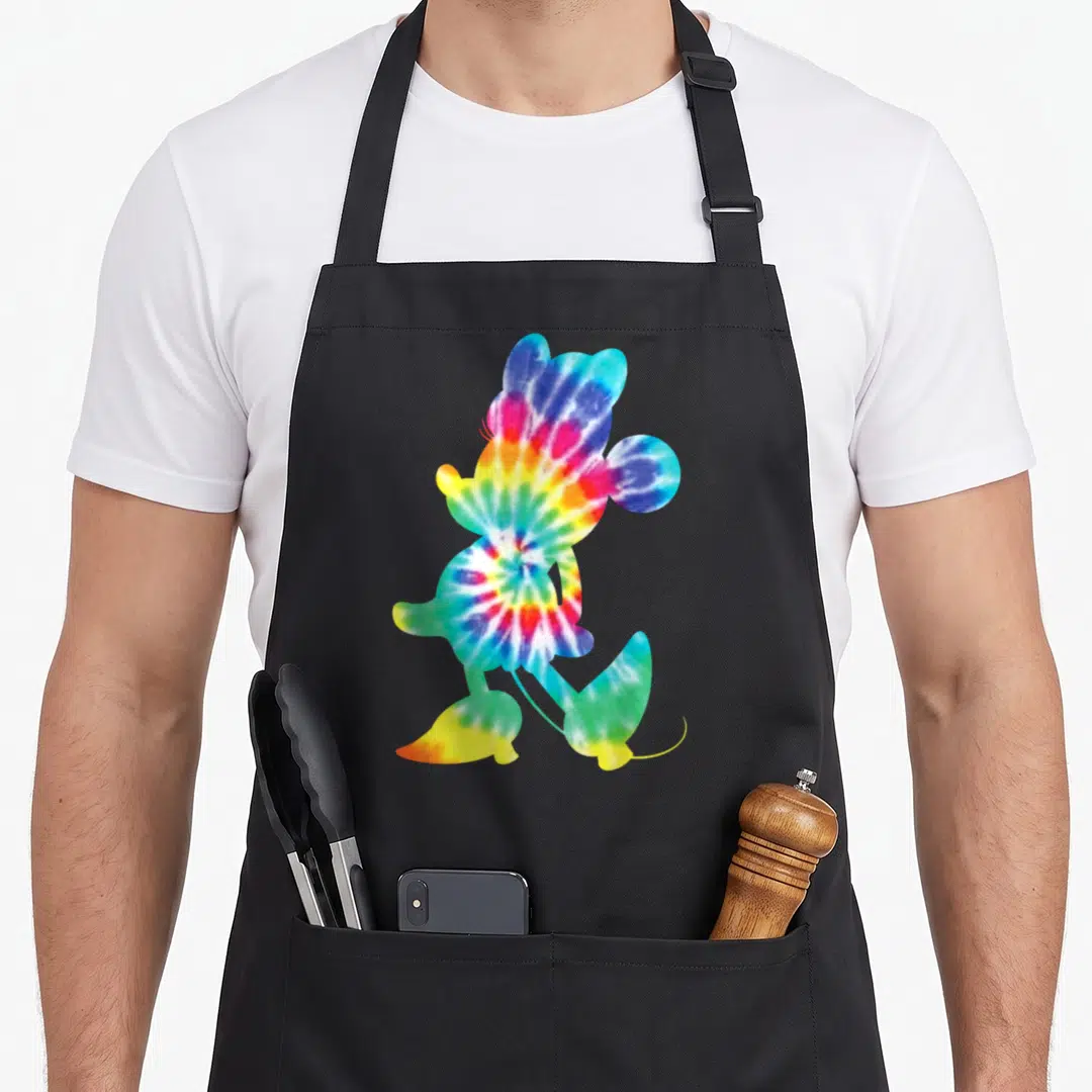90s tie dye apron - Walking mouse silhouette filled with red yellow green blue purple tie dye pattern — shown on a black cotton canvas apron against a white background