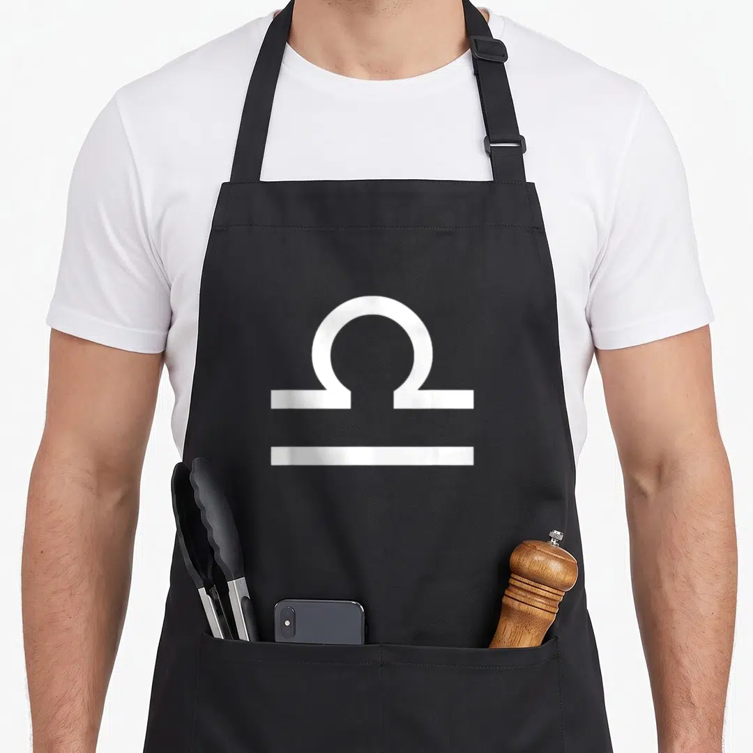 Libra zodiac aprons - Minimalist white Libra zodiac symbol centered on grey background — shown on a black cotton canvas apron against a white background