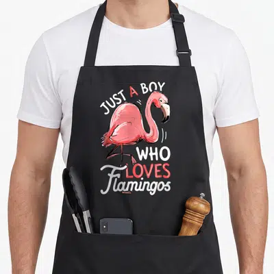 Funny bird pink flamingo apron - Watercolor pink flamingo with text Just A Boy Who Loves Flamingos — shown on a black cotton canvas apron against a white background