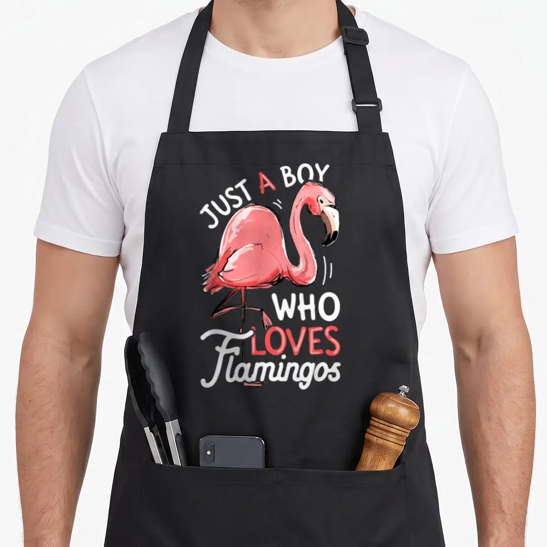Funny bird pink flamingo apron - Watercolor pink flamingo with text Just A Boy Who Loves Flamingos — shown on a black cotton canvas apron against a white background