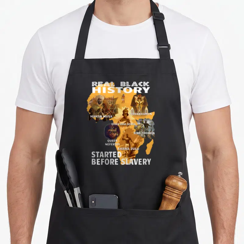 Didnt black history apron - Orange Africa map collage with Mansa Musa Tutankhamun Nzinga Nefertiti Taharoa Zulu text — shown on a black cotton canvas apron against a white background