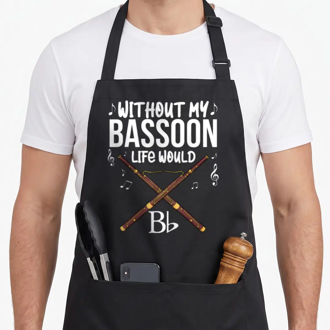 Jazz bassoon apron - Two crossed brown bassoons with yellow keys surrounded by white musical notes and stacked text — shown on a black cotton canvas apron against a white background