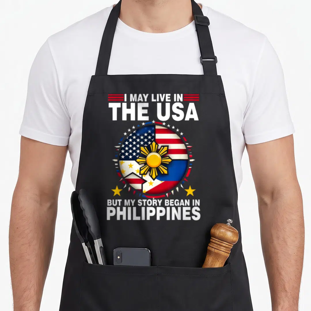 Root philippines apron - Combined US Philippines flag circle with I May Live In The USA But My Story Began — shown on a black cotton canvas apron against a white background