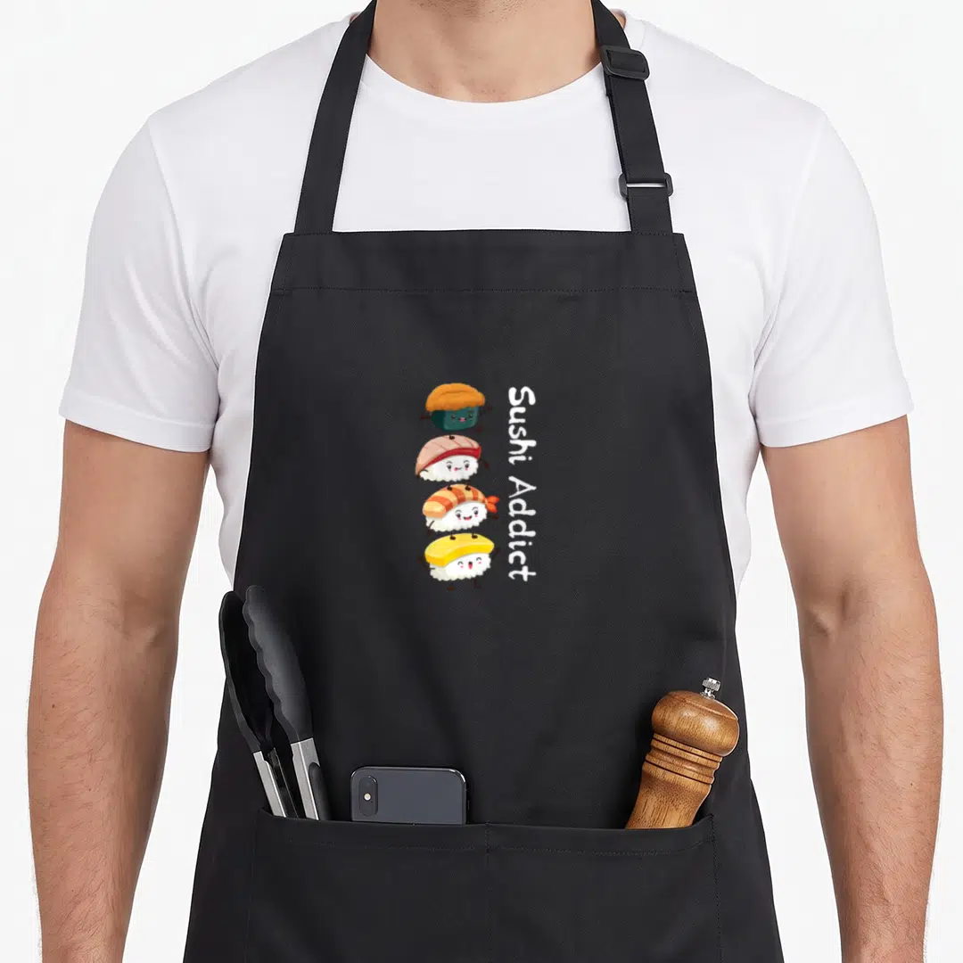 Addict sushi apron - Four stacked cartoon sushi characters with vertical Sushi Addict text in white and bright colors — shown on a black cotton canvas apron against a white background