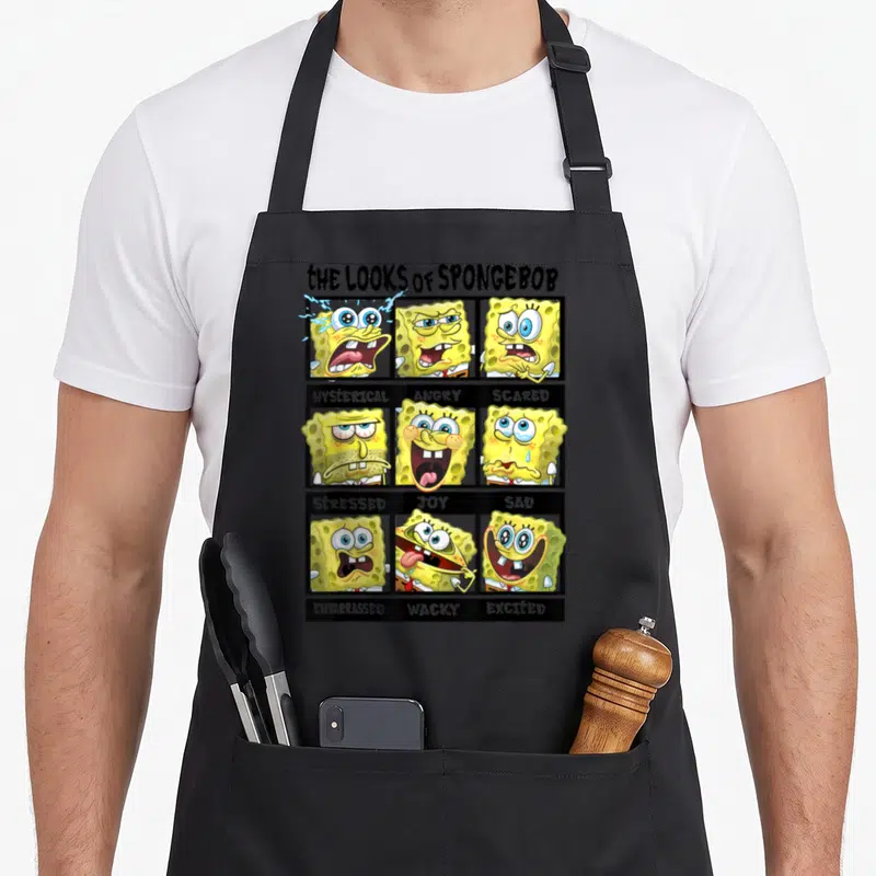 Multiple general apron - Nine SpongeBob cartoon faces in a grid labeled with emotions like angry, scared, and joyful — shown on a black cotton canvas apron against a white background